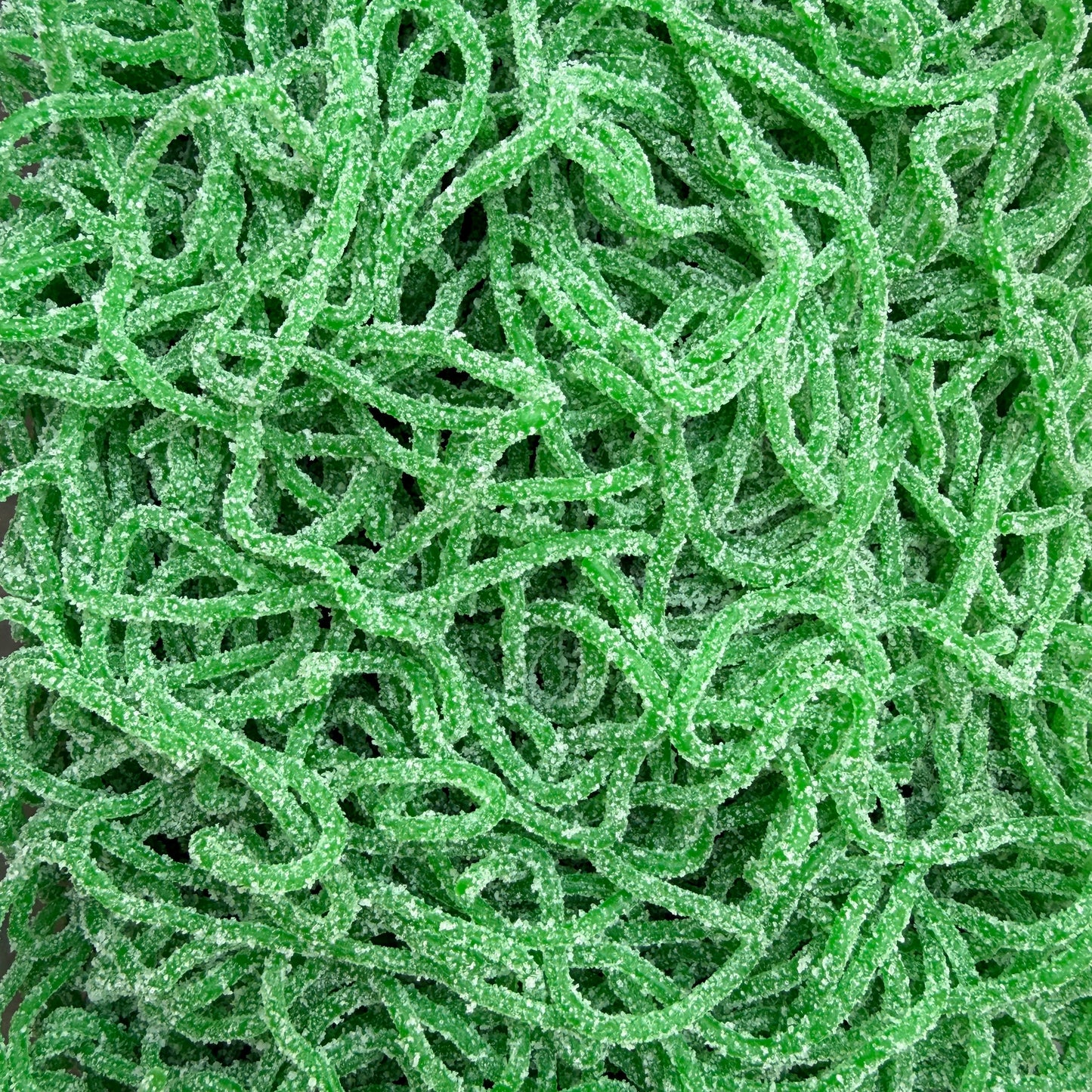 A close-up of bright green, sugar-coated, curly candy sticks filling the entire frame.